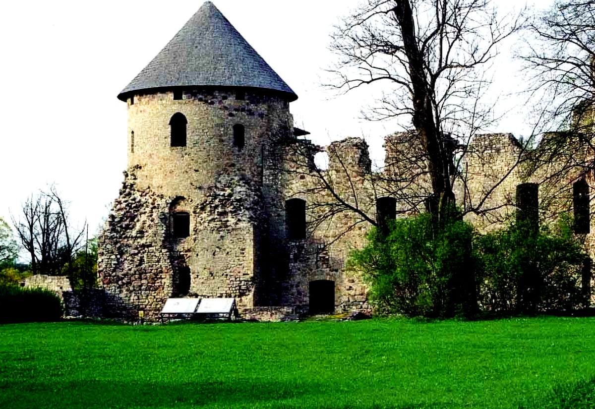 Castle with clock tower in middle of field (Cesis Castle, Cēsis, Latvia) - wallpaper